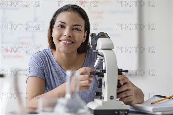 Smiling Hispanic woman using microscope