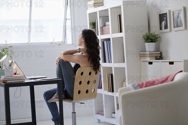 Hispanic businesswoman daydreaming in office