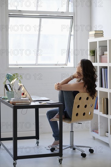 Hispanic businesswoman daydreaming in office