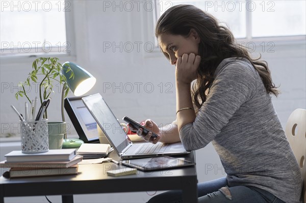 Hispanic businesswoman using technology in office