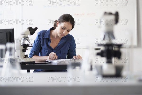 Hispanic professor grading papers in classroom