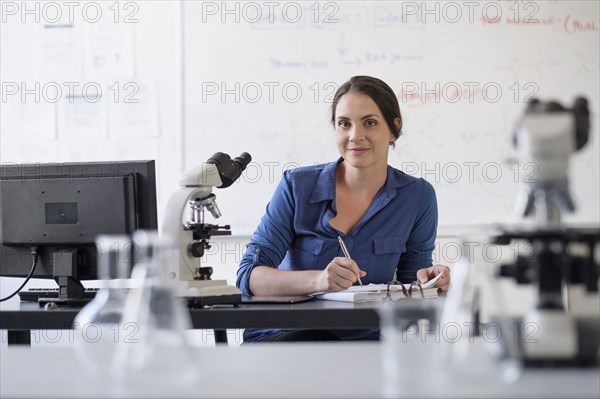 Smiling Hispanic professor grading papers in classroom