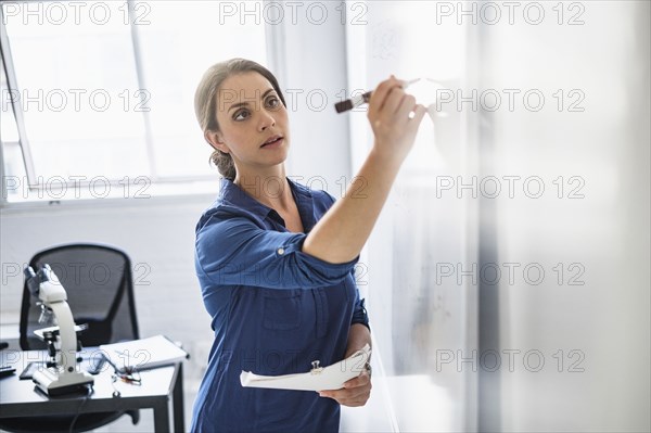 Hispanic professor writing on whiteboard