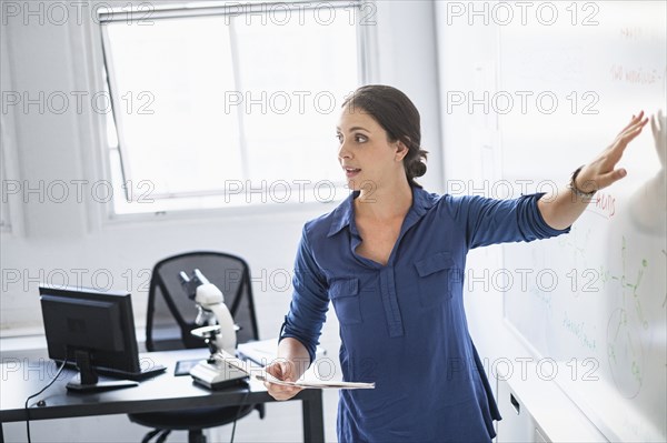 Hispanic professor pointing to whiteboard