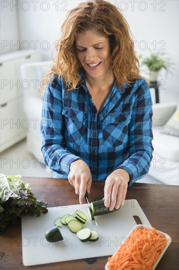 Smiling Caucasian woman slicing cucumbers