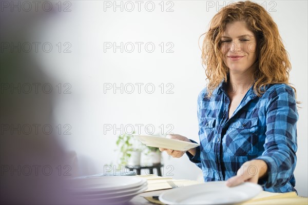 Smiling Caucasian woman setting table for meal