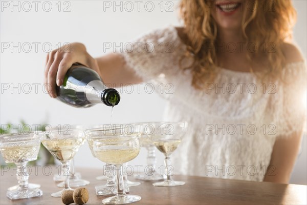 Smiling Caucasian woman pouring champagne into coupes