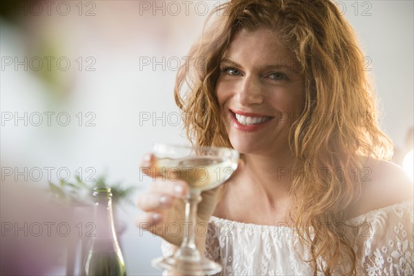 Smiling Caucasian woman drinking champagne in coupe