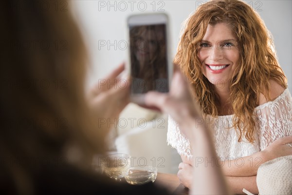 Friend photographing Caucasian woman with cell phone