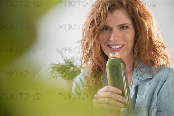 Smiling Caucasian woman drinking green smoothie