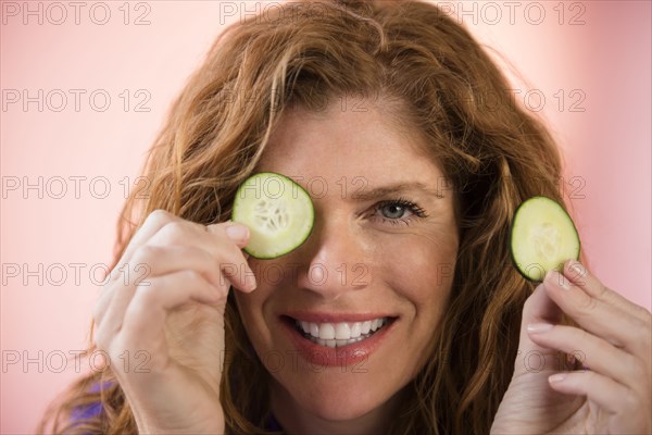 Smiling Caucasian woman covering eye with cucumber slice