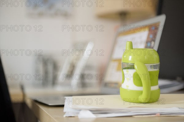 Sippy cup on file folder near laptop