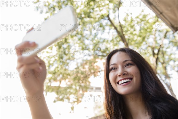 Smiling Thai woman posing for cell phone selfie
