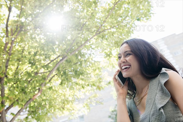 Thai woman talking on cell phone under tree