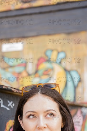 Face of Thai woman near graffiti on urban wall