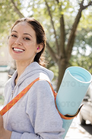 Thai woman posing in city carrying exercise mat