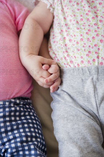 Caucasian twin baby girls holding hands