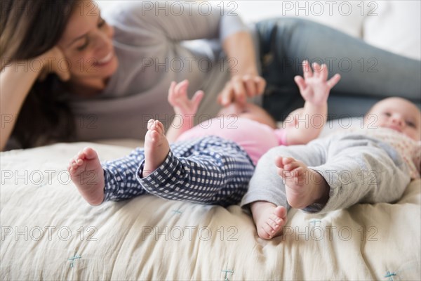 Caucasian mother playing with twin baby daughters on bed