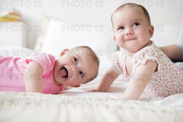 Happy Caucasian twin baby girls on bed