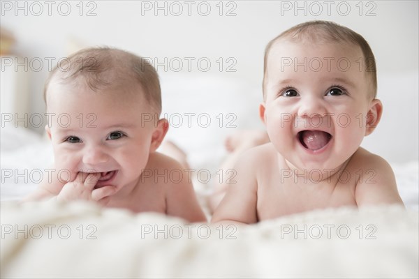 Caucasian twin baby girls smiling on bed