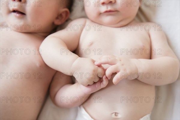 Caucasian twin baby girls holding hands