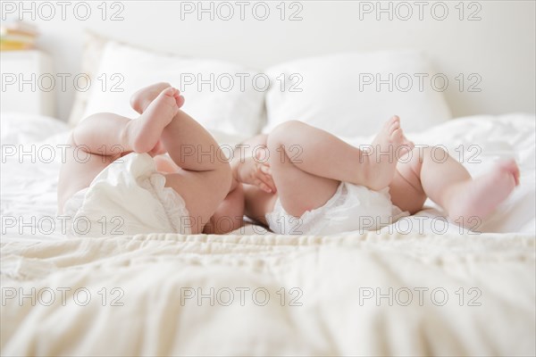 Legs of Caucasian twin baby girls laying on bed