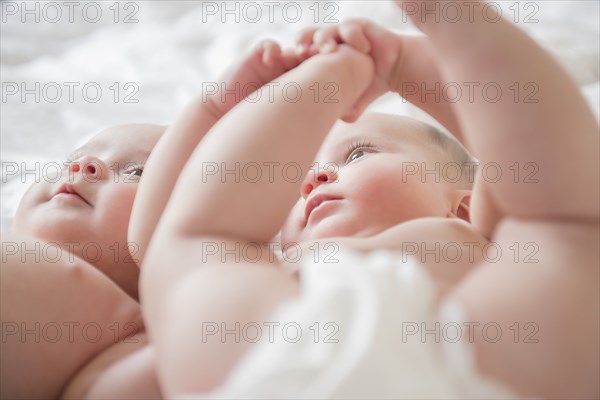 Caucasian twin baby girls laying on bed