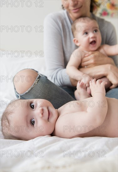 Caucasian mother with twin baby daughters on bed