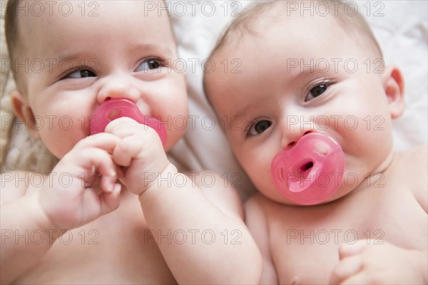 Caucasian twin baby girls sucking pacifiers