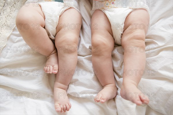 Legs of Caucasian twin baby girls laying on bed