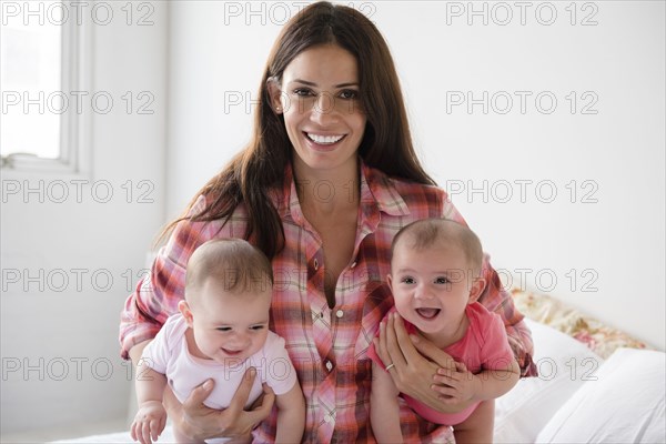 Caucasian mother holding twin baby daughters
