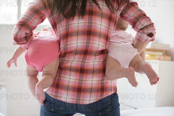 Caucasian mother holding twin baby daughters