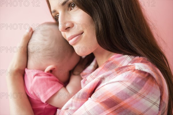 Caucasian mother hugging baby daughter