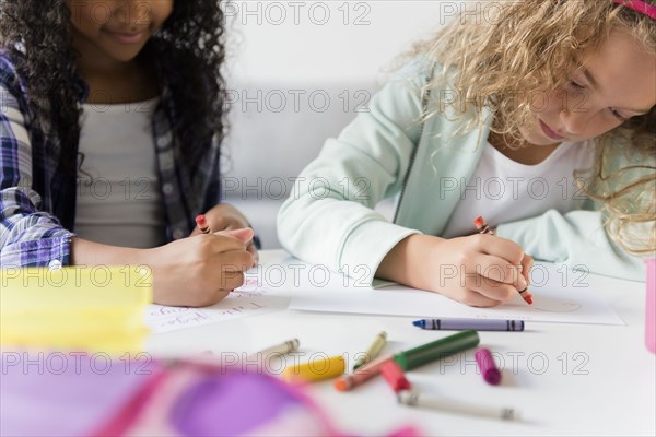 Girls drawing with multicolor crayons