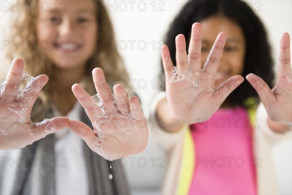 Girls showing palm of hands with soap suds