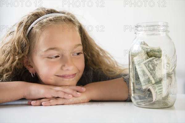 Smiling girl saving money in jar