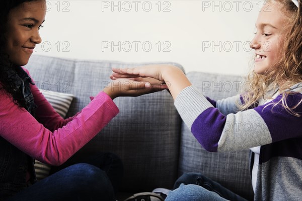Smiling girls playing game with hands on sofa