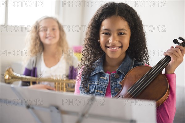 Smiling girls posing with violin and trumpet