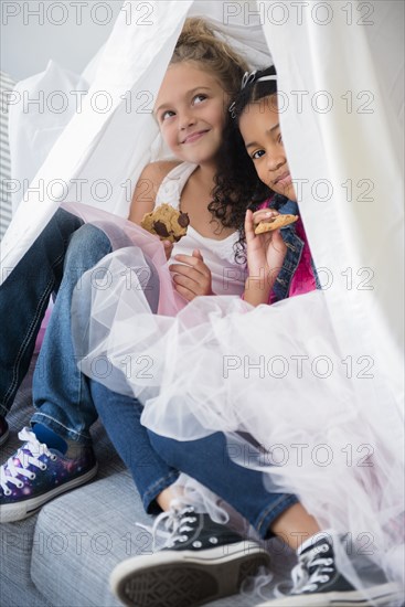 Girls wearing tutus in blanket fort on sofa