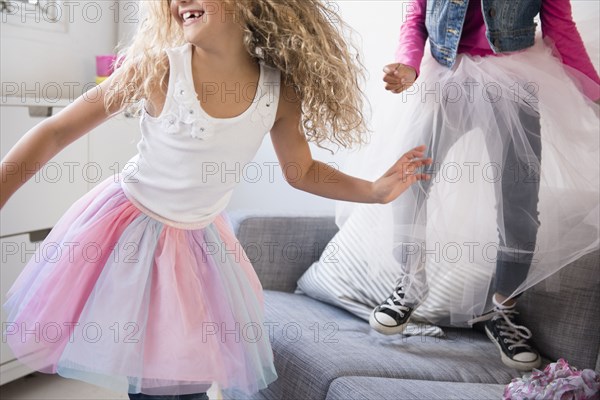 Girls wearing tutus dancing on sofa