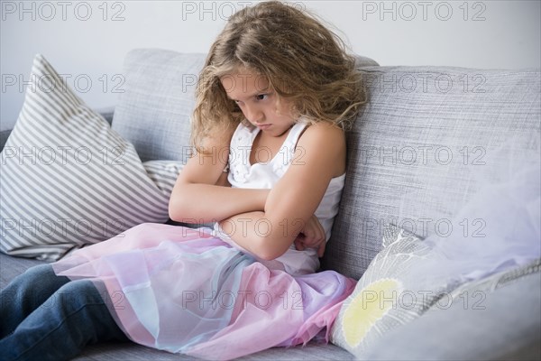 Frustrated girl wearing tutu pouting on sofa