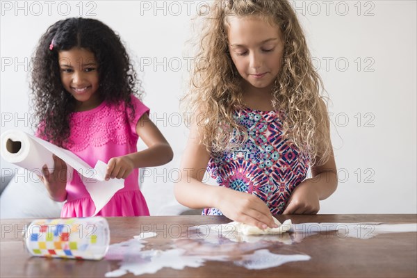 Girls cleaning spilled milk on table