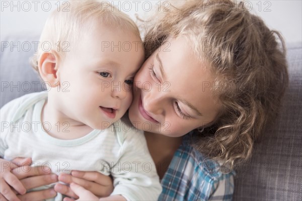Smiling Caucasian girl holding baby brother