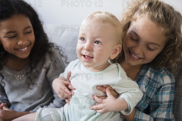 Friend watching smiling girl holding baby brother