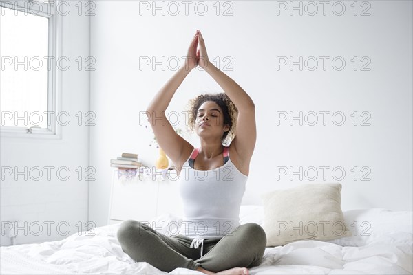 Mixed Race woman sitting on bed meditating