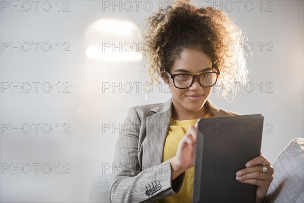 Mixed Race woman wearing eyeglasses using digital tablet