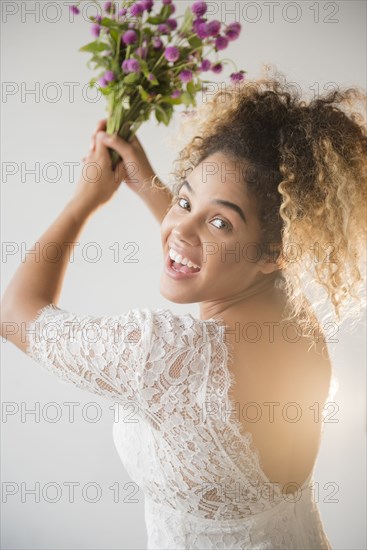 Mixed Race woman wearing wedding dress tossing bouquet