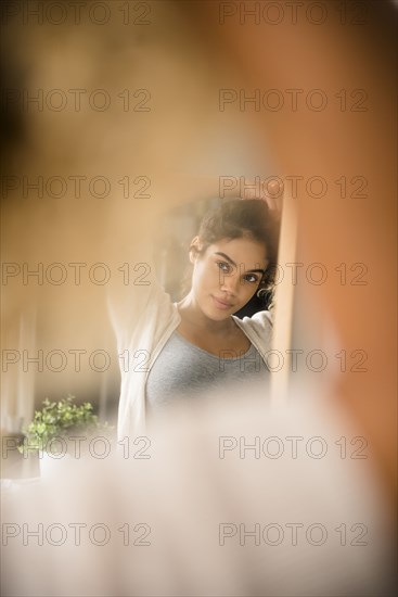 Reflection in mirror of Mixed Race woman holding hair