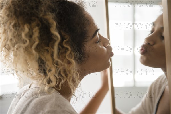 Mixed Race woman puckering lips in mirror