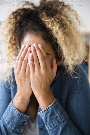 Mixed Race woman covering face with hands